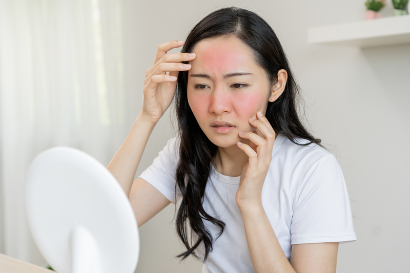 woman with red face checking mirror